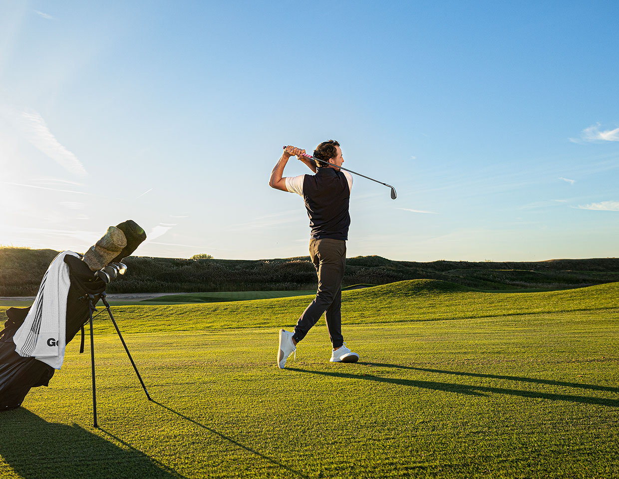man swinging a golf club on a green