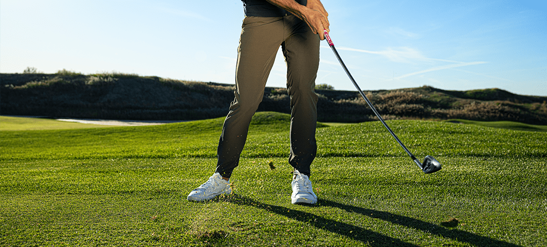Man chipping a ball woth grass flying up from swing